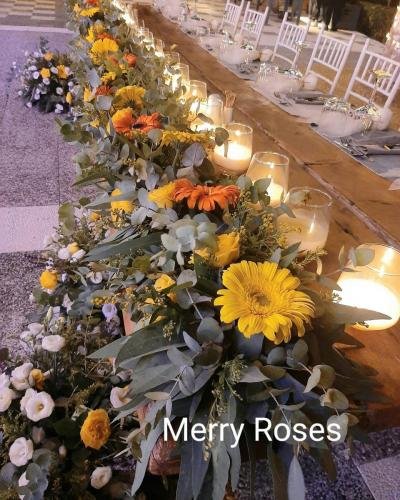 Νυφικό τραπέζι με γιρλάντα απο ποικιλία χρωμάτων λουλουδιών και κηροπήγεια.